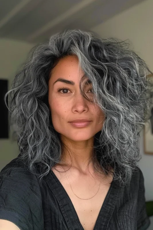 Woman with textured curly salt and pepper hair.
