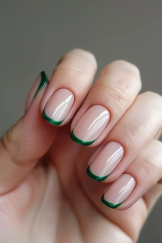 Short rounded nails with dark green French tips.