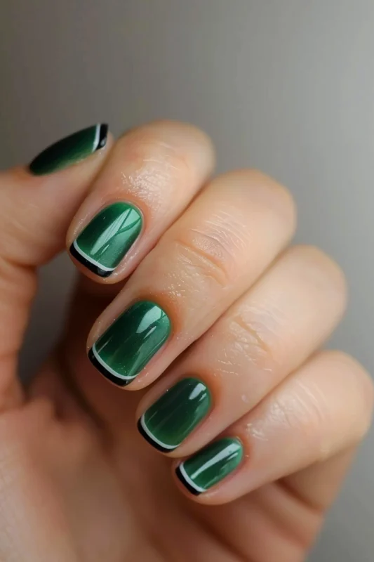 Glossy green nails with black and white bordered tips.