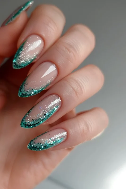 Modern French manicure with shimmering seafoam tips and glitter.