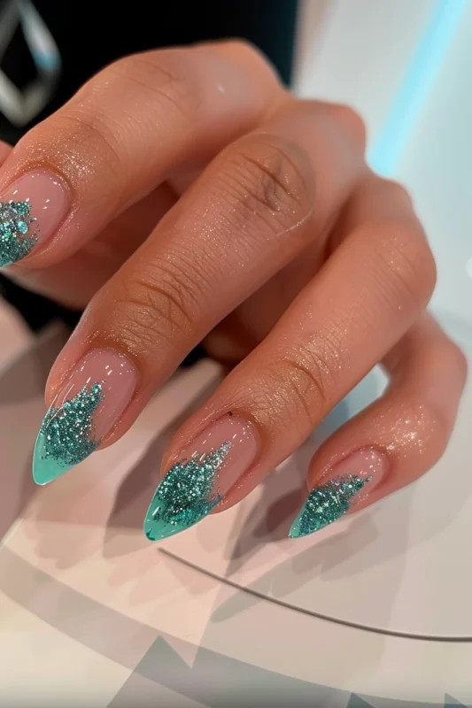 Nails with a sparkling emerald gradient and clear turquoise tips.