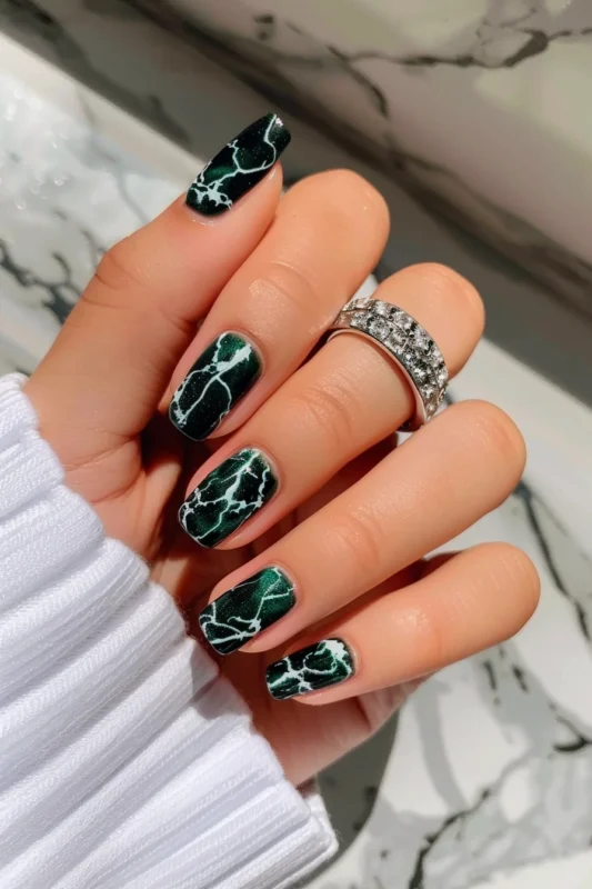 Nails with a dark green and white marble effect.