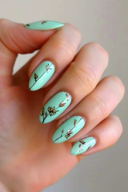 Mint green oval nails with botanical illustrations.