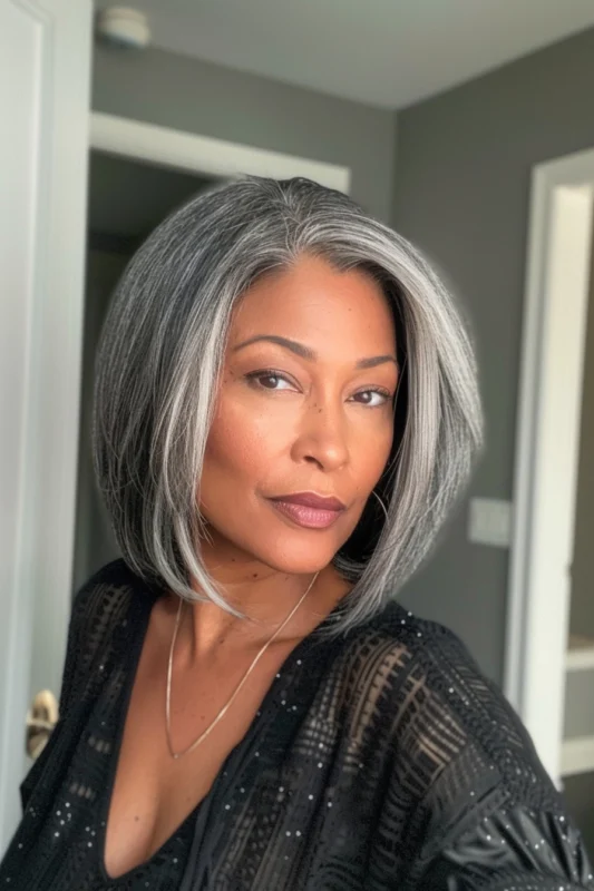 A woman with a sleek salt and pepper bob and a deep side part.