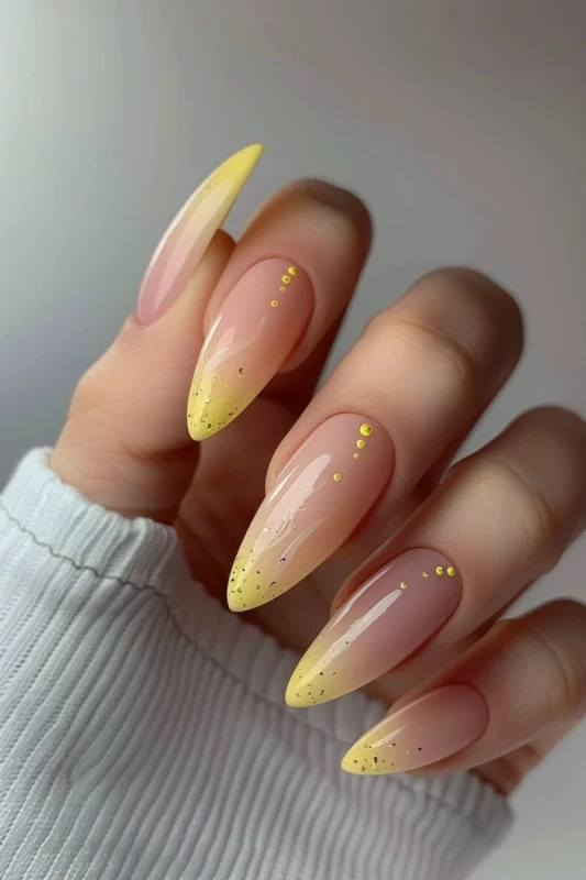 Ombre yellow French tip nails with golden glitter.