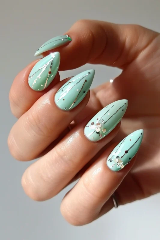 Pastel green stiletto nails with gold speckles and sequins.