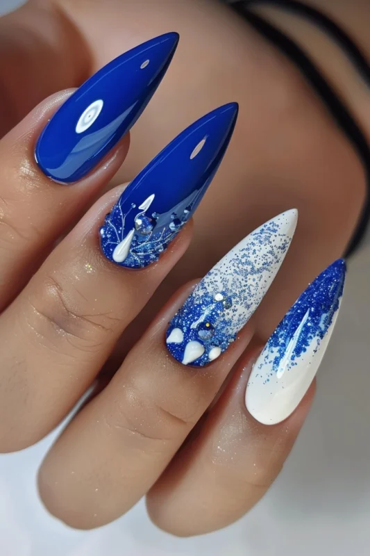 Stiletto-shaped nails with royal blue, white accents, and glitter.