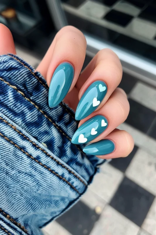 Teal blue nails with white heart patterns.