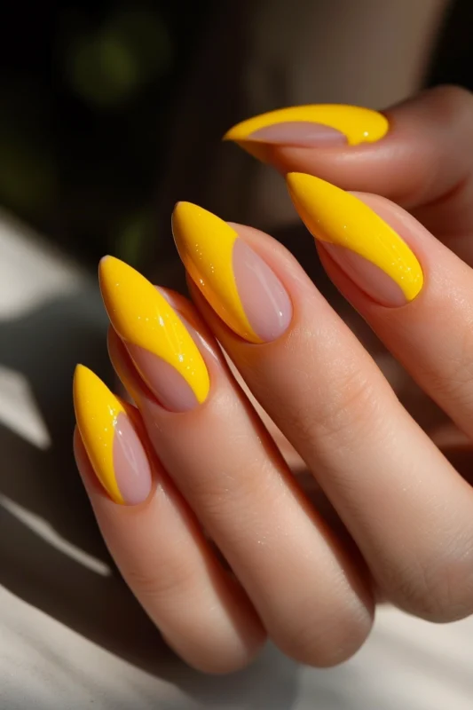 Glossy yellow French nails in stiletto shape.