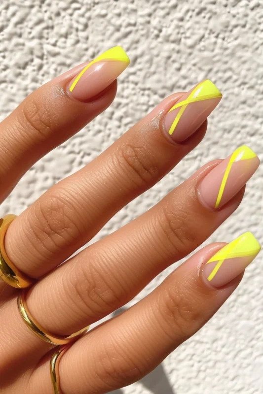 Geometric yellow French tips on coffin-shaped nails.