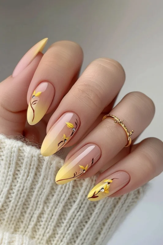 Yellow French tip nails in ombre style with brown branches and gold flowers