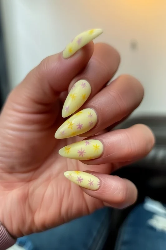 Yellow nails with purple and dark yellow stars on a stiletto shape