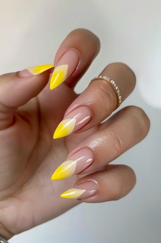 Stiletto-shaped nails with gradient tips transitioning from dark yellow to light yellow.