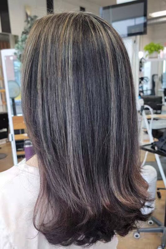 Dark hair with chunky warm blonde highlights to blend first grays.