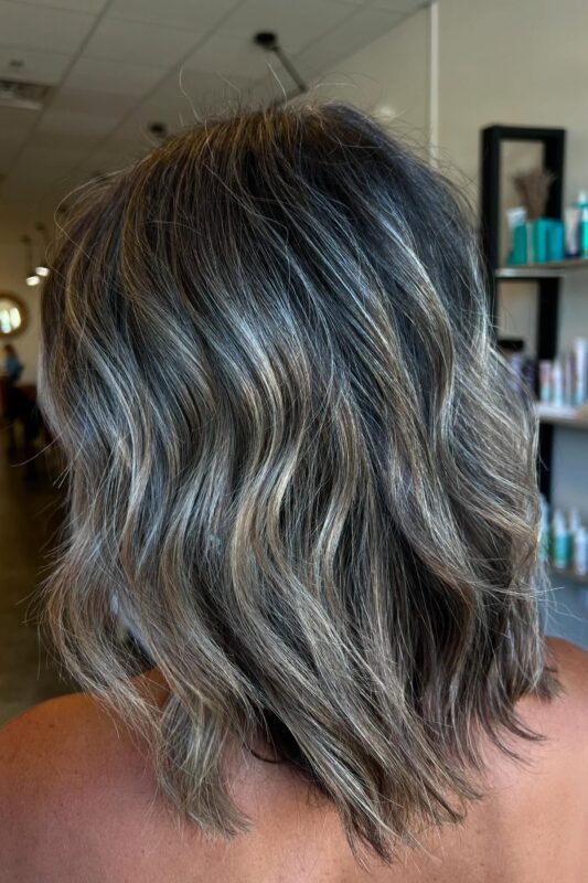 Black hair with cool-toned ashy balayage highlights for gray blending.