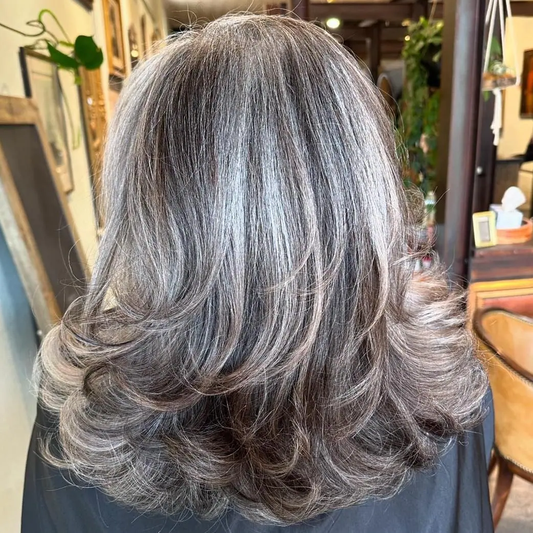 Woman with chunky salt and pepper highlights on long layers.