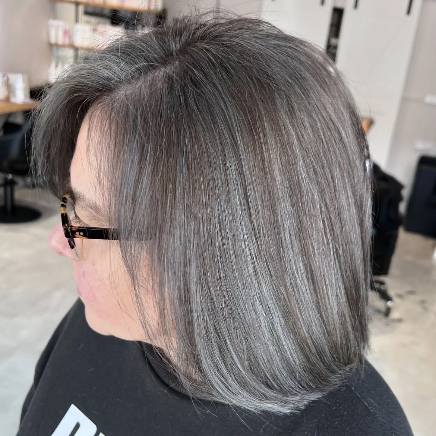 Woman with a medium-length dark brown and gray hair combo.