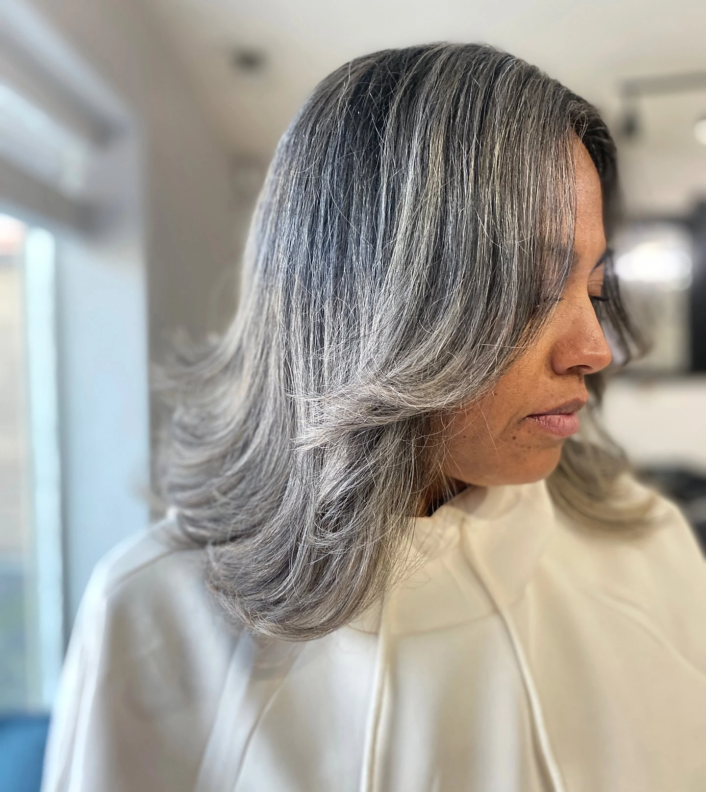 Woman with shoulder-length dark hair featuring streaks of gray.