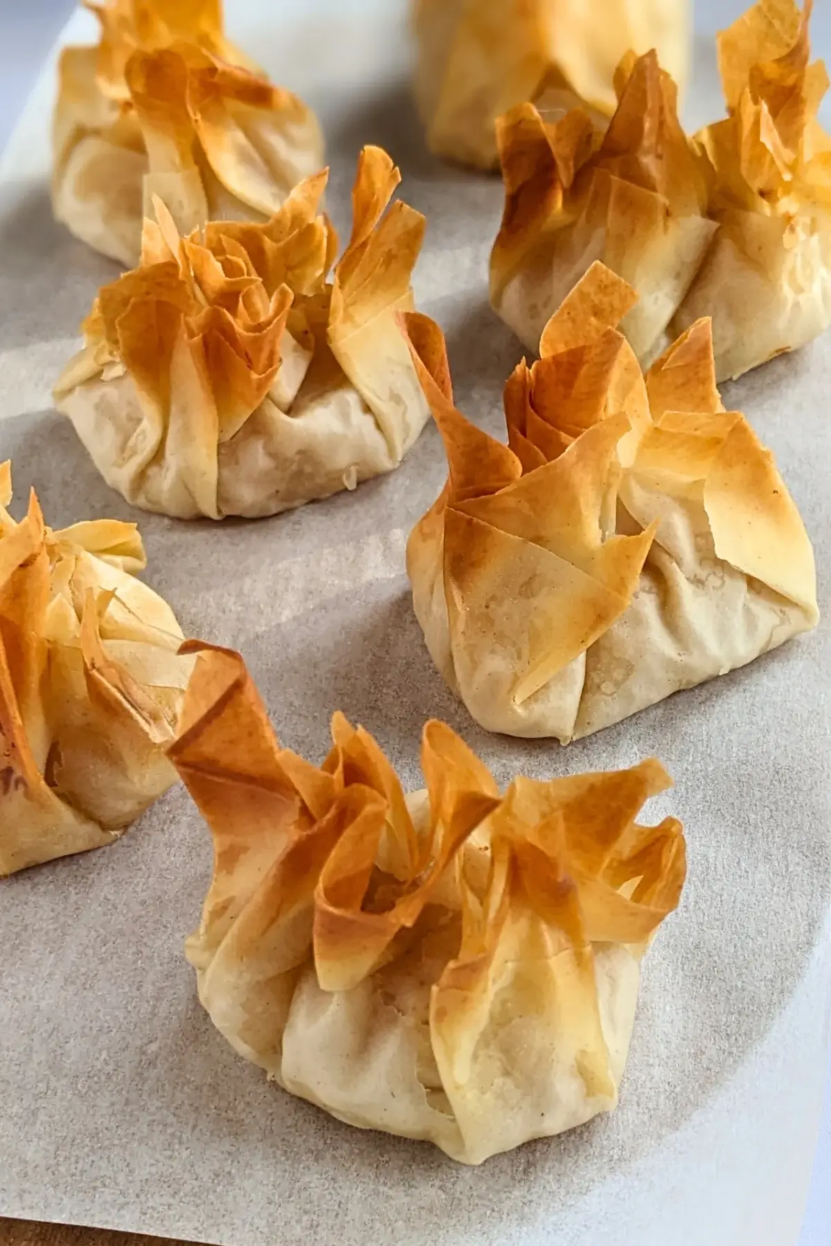 Golden phyllo pastry dessert parcels filled with ricotta and homemade apple sauce, lightly crisped.