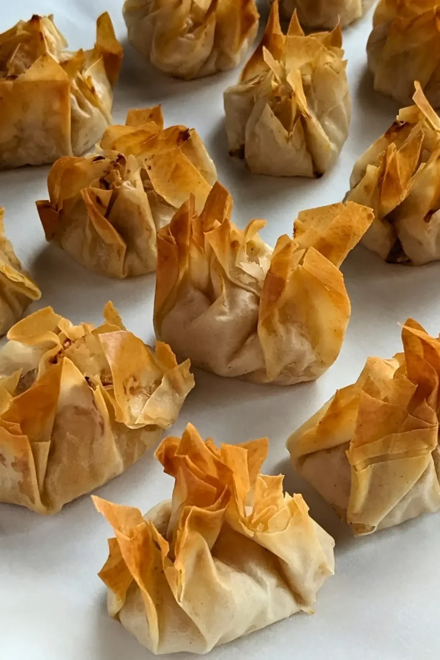 Golden phyllo pastry dessert parcels filled with ricotta and homemade apple sauce, lightly crisped.