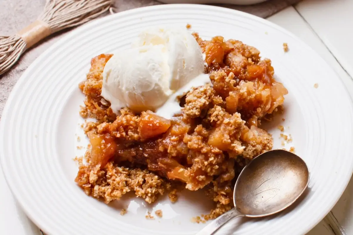 Fruit-filled apple crumble with a golden, crumbly topping and chunks of rhubarb and apple at the bottom.