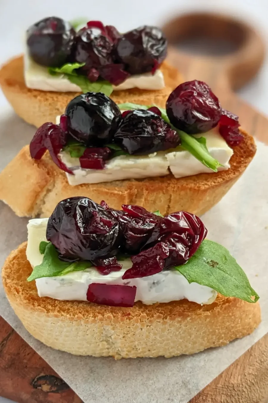 Blueberry and brie crostini appetizers - toasted bread slices topped with balsamic stewed blueberries, creamy Brie cheese and arugula.