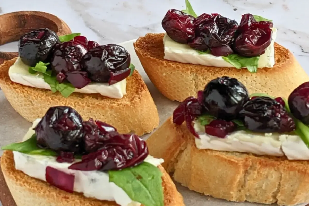 Blueberry and brie crostini appetizers - toasted bread slices topped with balsamic stewed blueberries, creamy Brie cheese and arugula.
