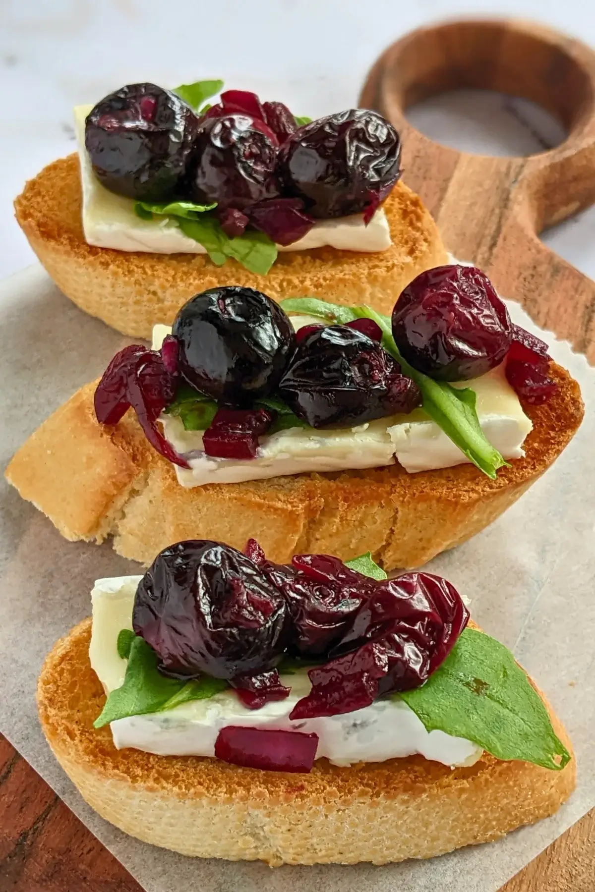 Blueberry and brie crostini appetizers - toasted bread slices topped with balsamic stewed blueberries, creamy Brie cheese and arugula.
