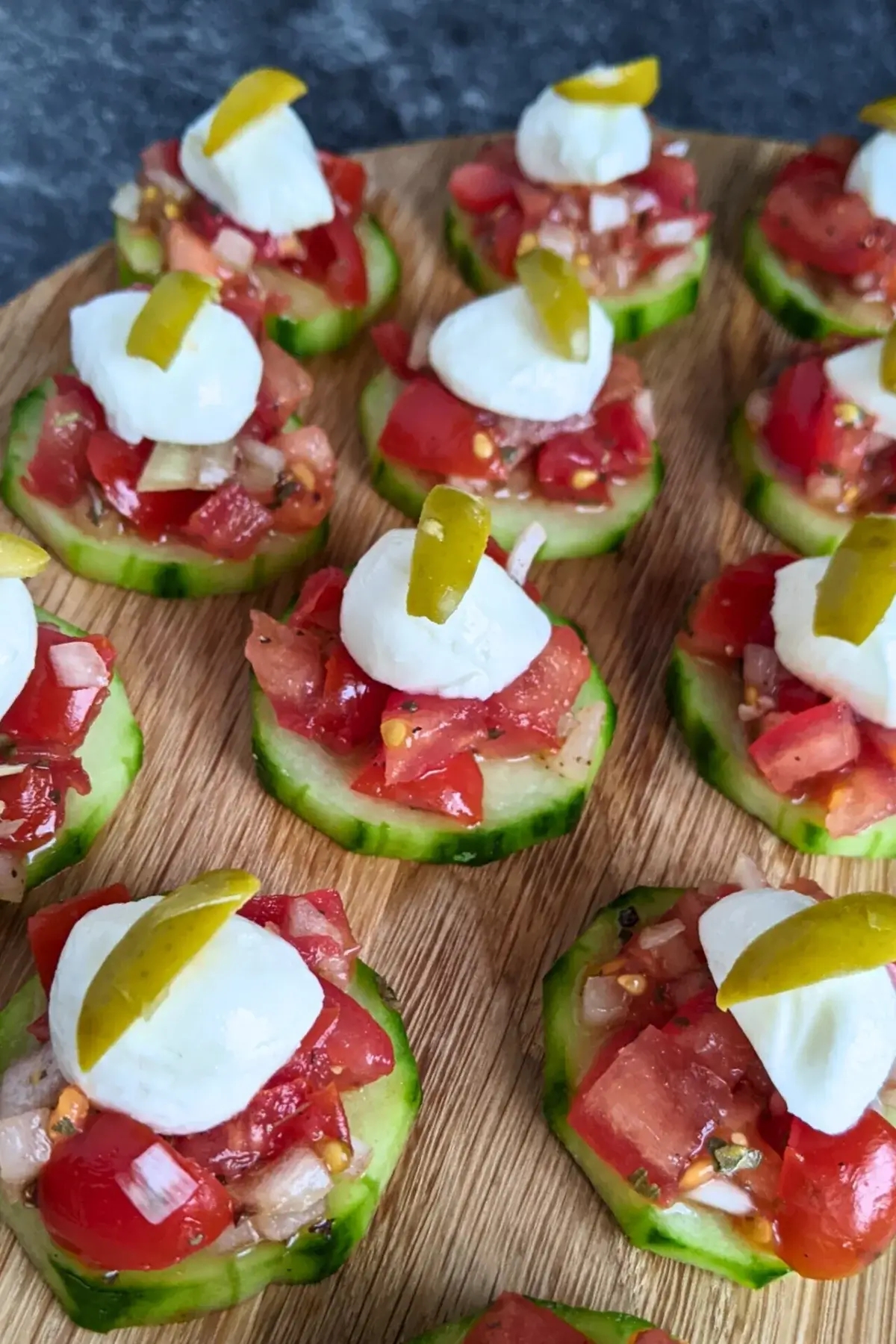 Fresh bruschetta cucumber bites appetizers topped with mozzarella balls and sliced olives, neatly arranged on a serving tray.