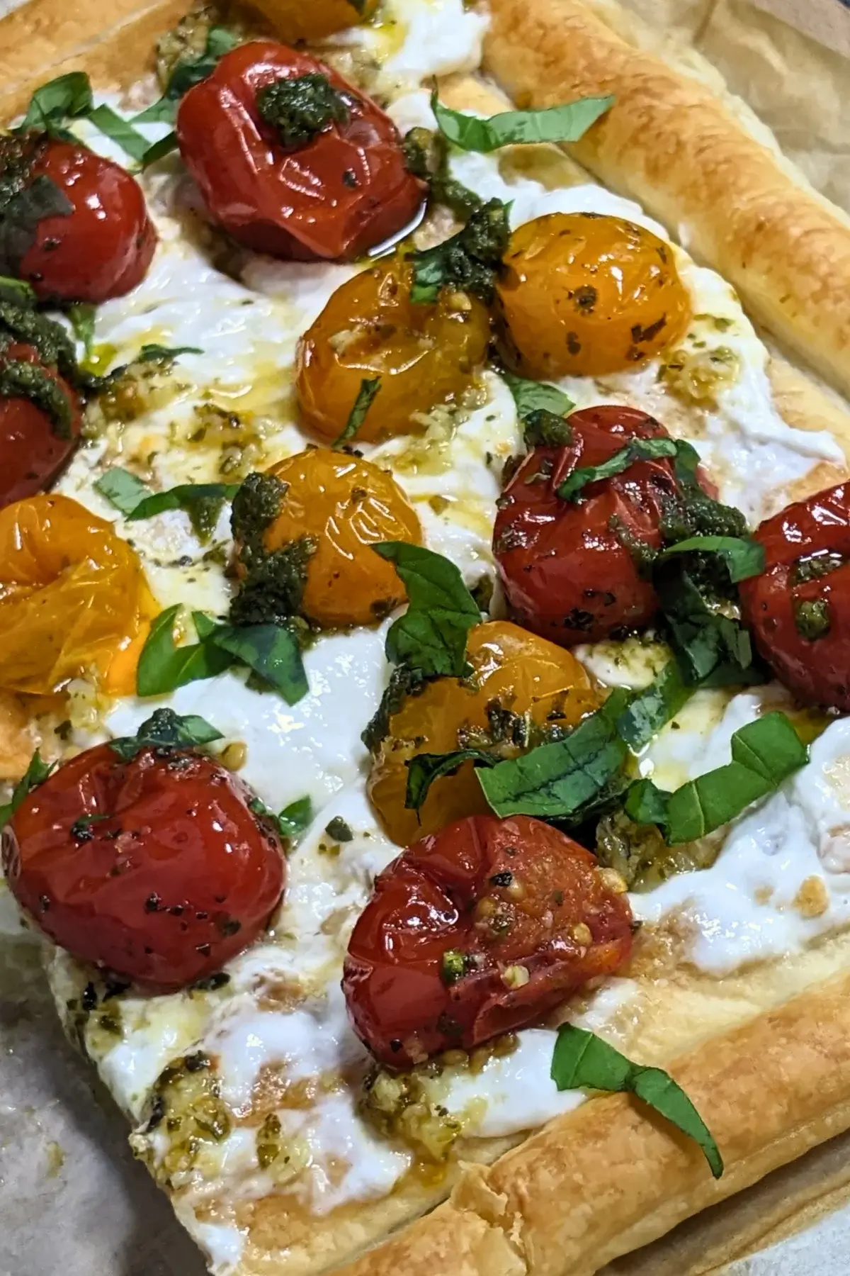 Cherry tomato and burrata appetizer with puff pastry, pesto, and fresh shredded basil.