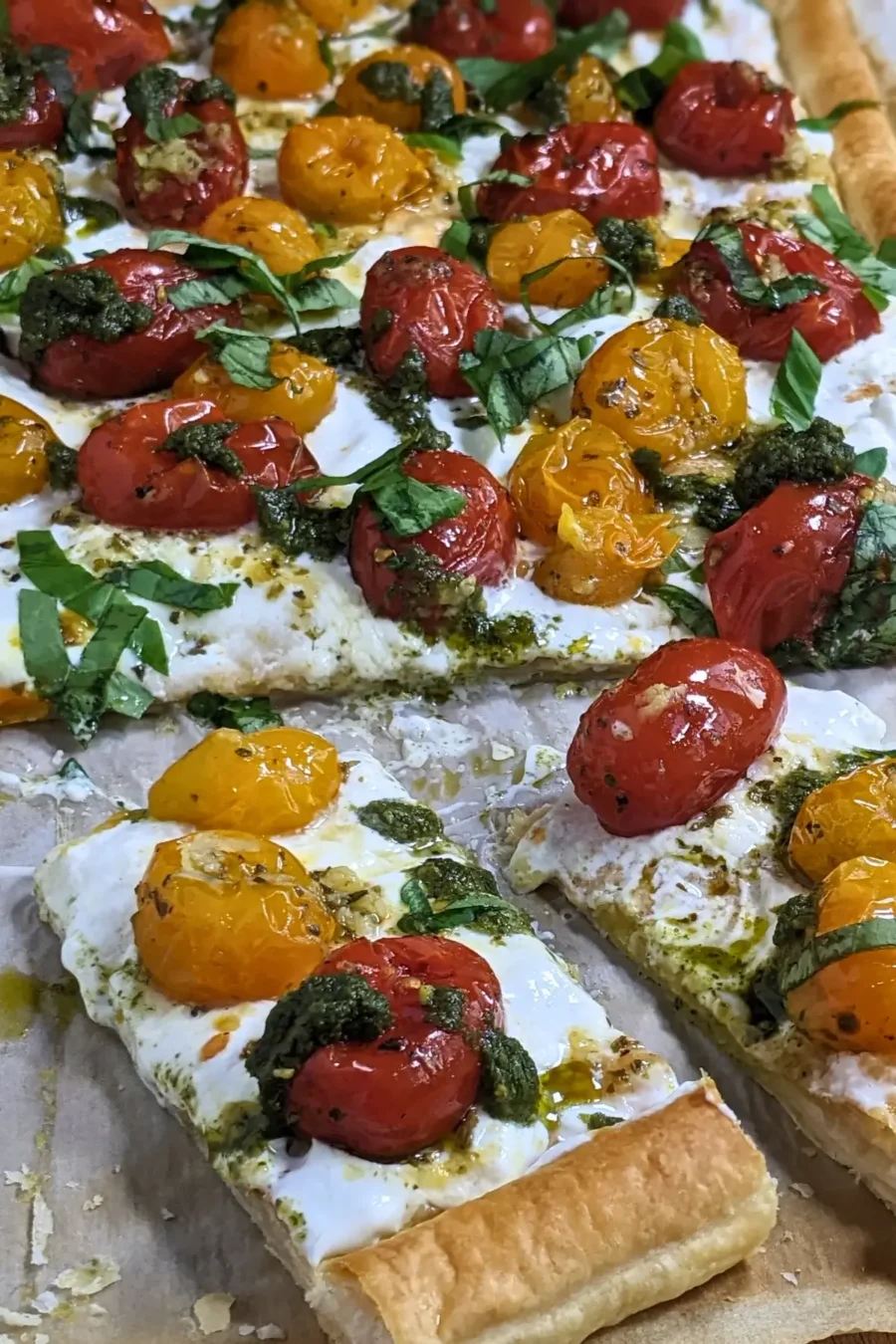 Cherry tomato and burrata appetizer with puff pastry, pesto, and fresh shredded basil.