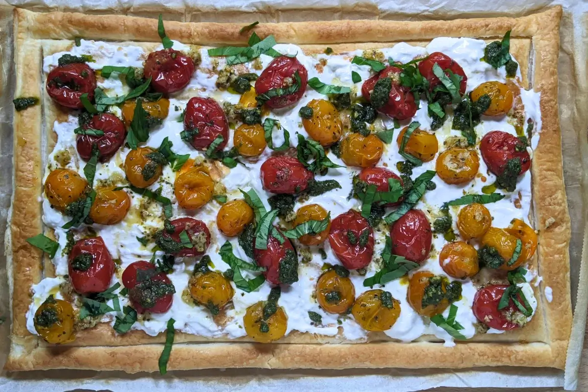 Cherry tomato and burrata appetizer with puff pastry, pesto, and fresh shredded basil.