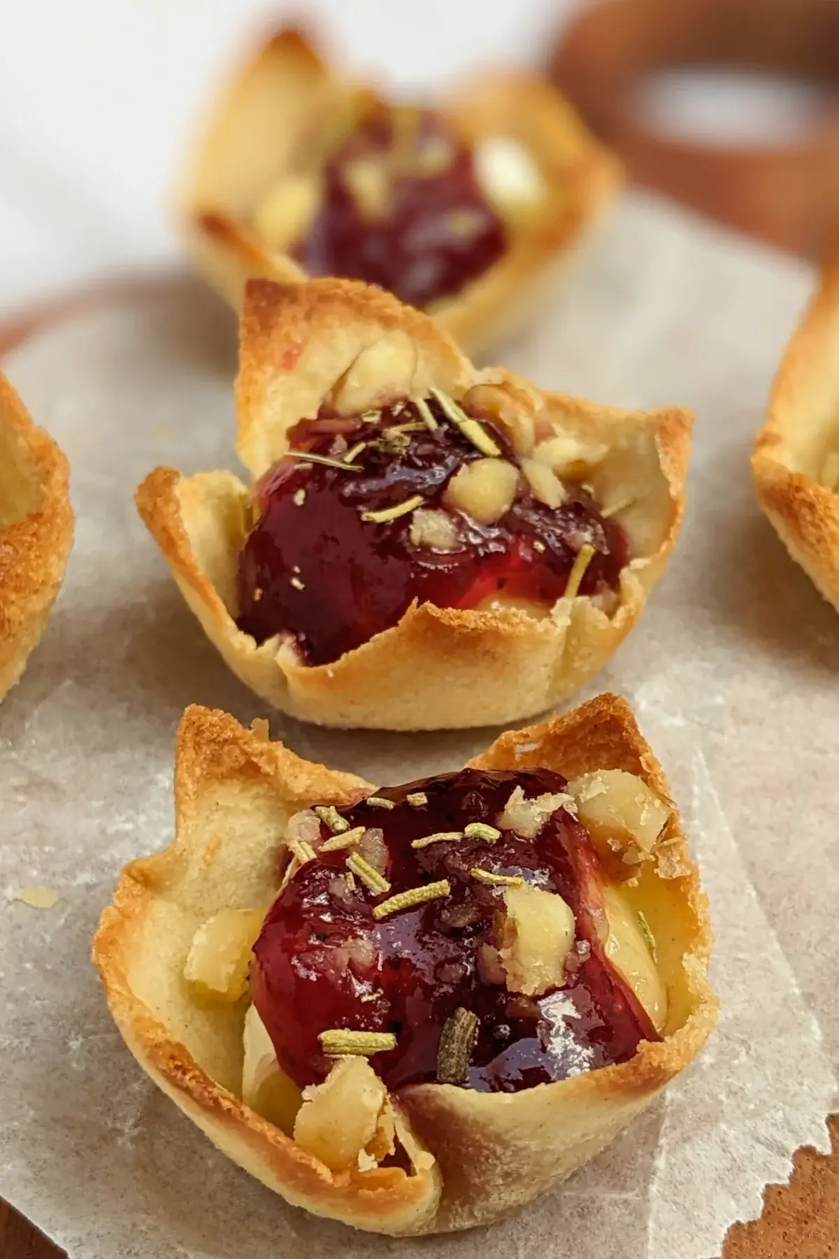 Cranberry brie bites - mini toast cup appetizers filled with brie cheese, topped with cranberry jam and crushed walnuts