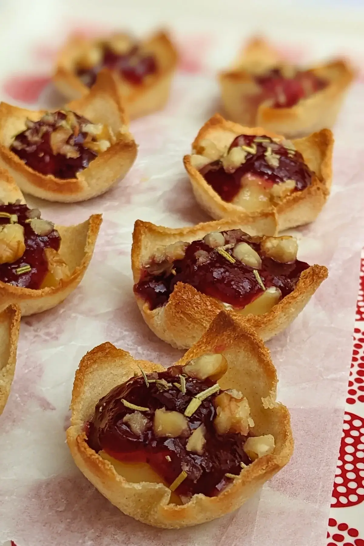 Cranberry brie bites - mini toast cup appetizers filled with brie cheese, topped with cranberry jam and crushed walnuts