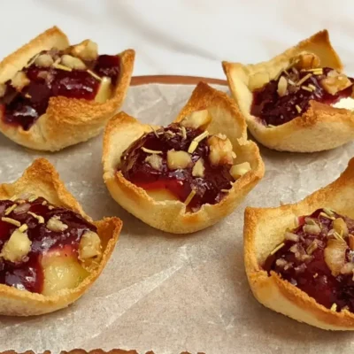 Cranberry brie bites - mini toast cup appetizers filled with brie cheese, topped with cranberry jam and crushed walnuts