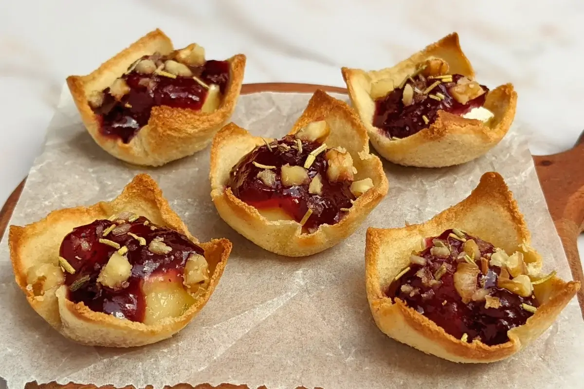 Cranberry brie bites - mini toast cup appetizers filled with brie cheese, topped with cranberry jam and crushed walnuts