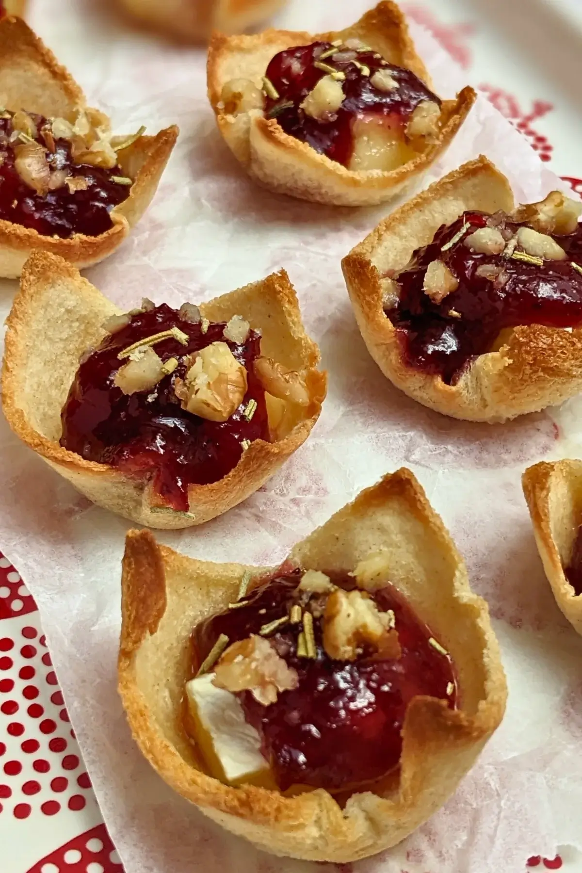 Cranberry brie bites - mini toast cup appetizers filled with brie cheese, topped with cranberry jam and crushed walnuts