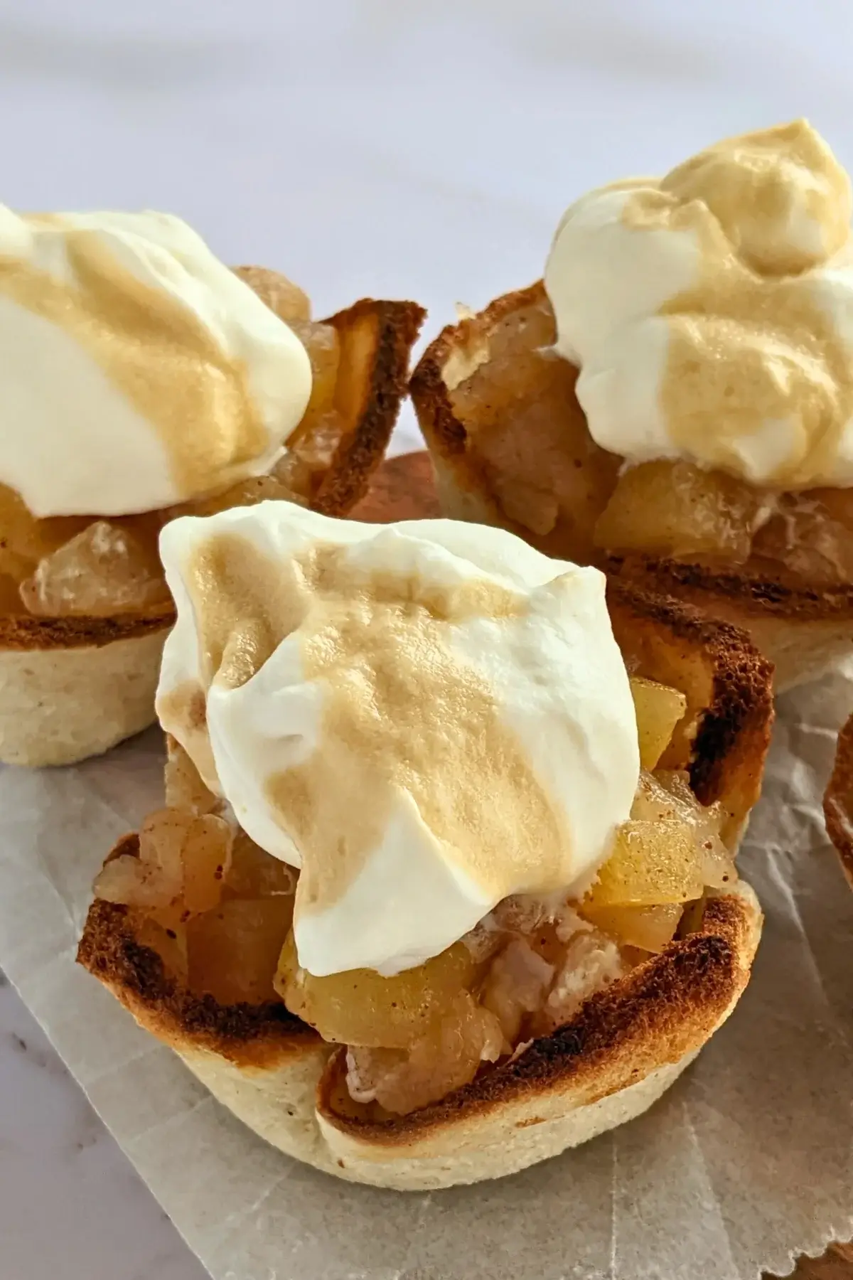 Homemade apple sauce dessert toast cups with whipped cream - Toasted bread cups filled with applesauce and finished with a swirl of whipped cream.