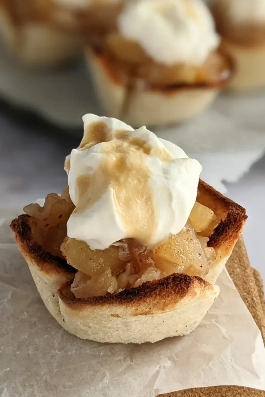 Homemade apple sauce dessert toast cups with whipped cream - Toasted bread cups filled with applesauce and finished with a swirl of whipped cream.