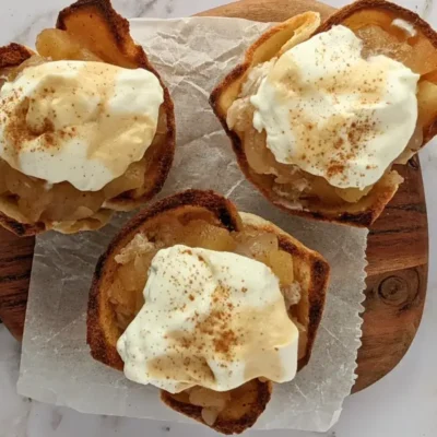Homemade apple sauce dessert toast cups with whipped cream - Toasted bread cups filled with applesauce and finished with a swirl of whipped cream.