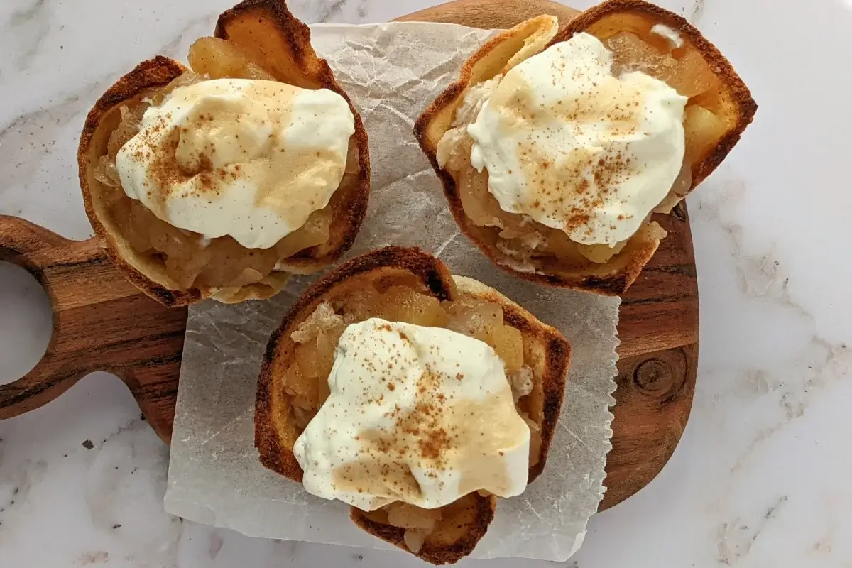 Homemade apple sauce dessert toast cups with whipped cream - Toasted bread cups filled with applesauce and finished with a swirl of whipped cream.