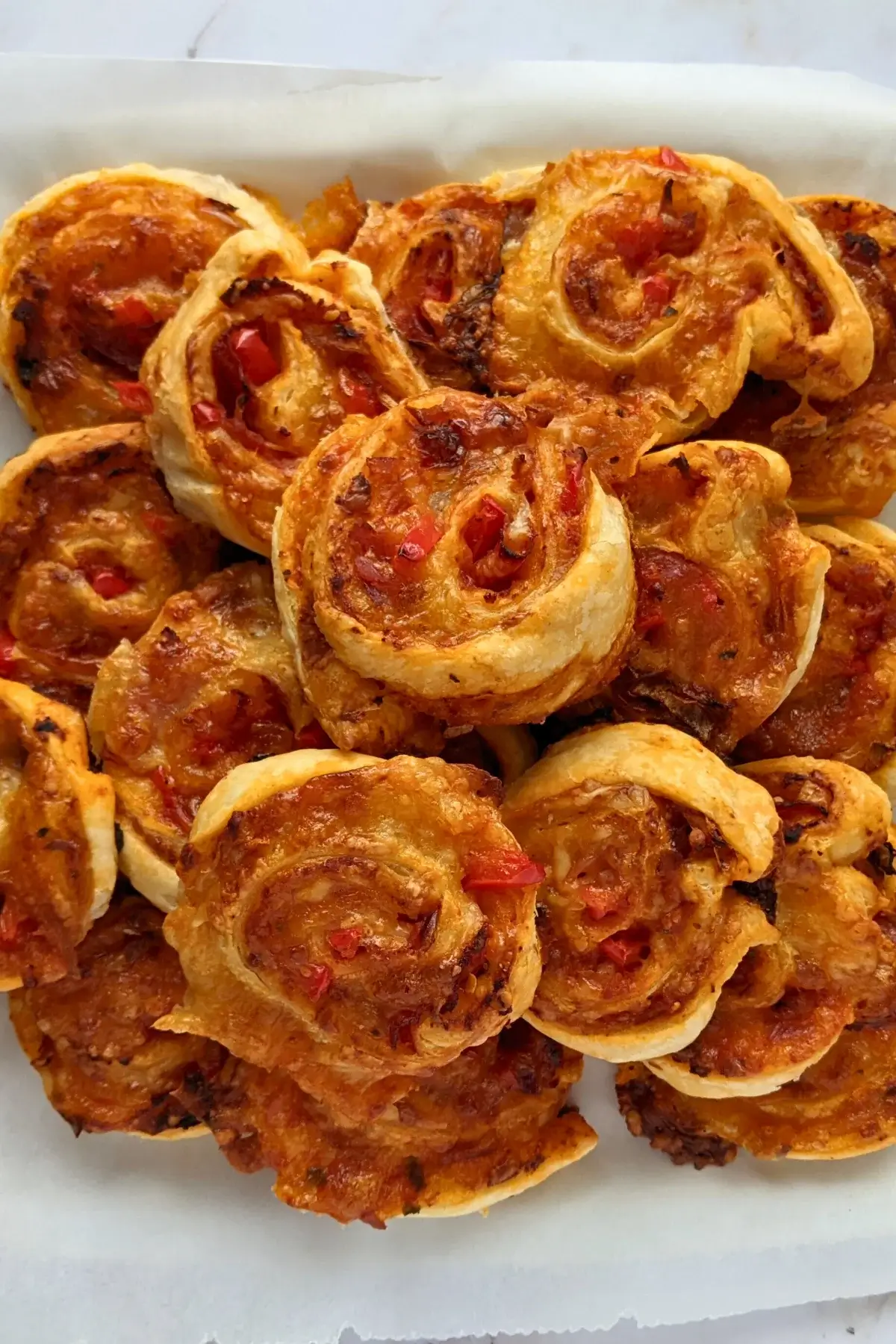 Golden brown pizza pinwheels filled with tomato sauce, salami, and melted cheese.