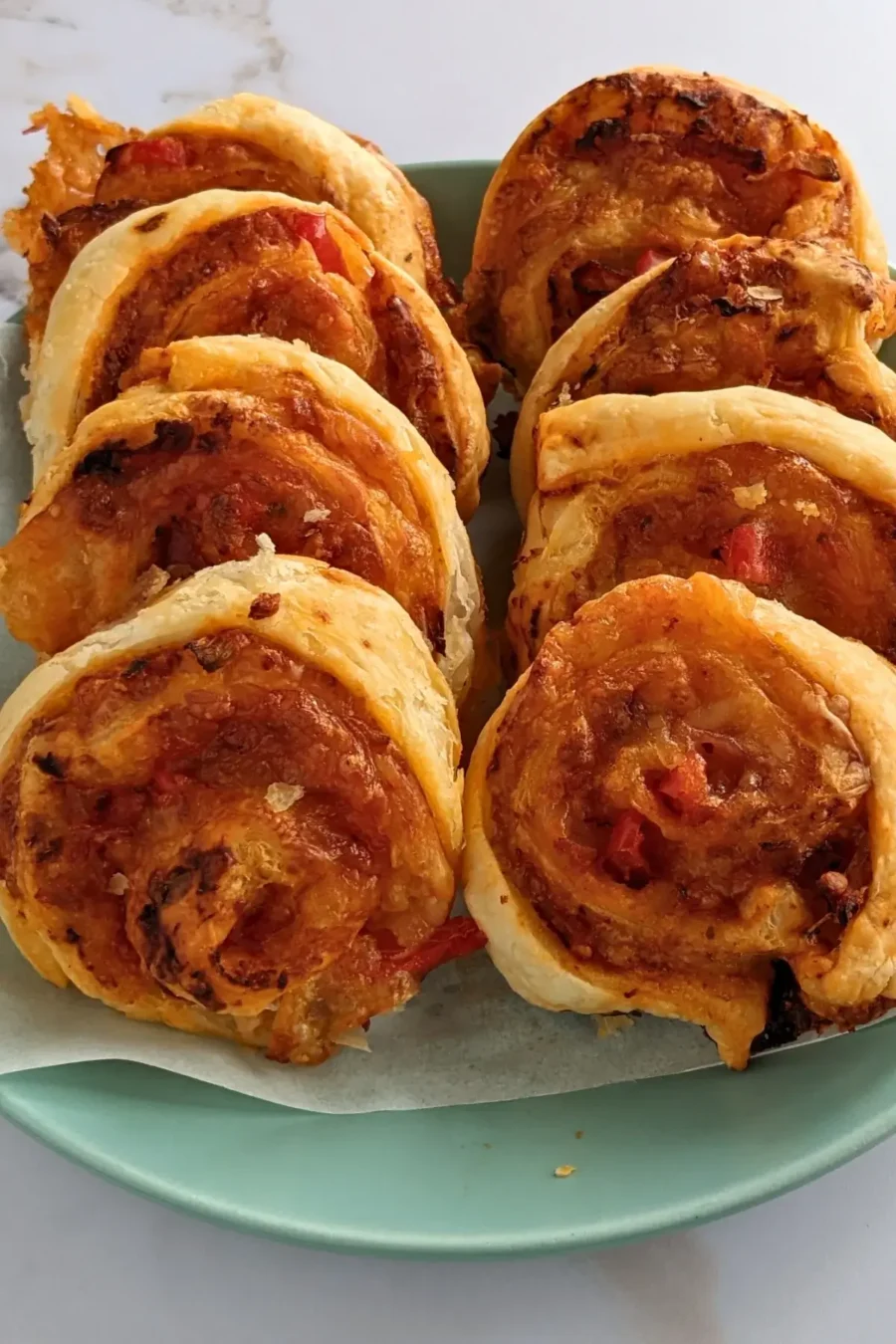 Golden brown pizza pinwheels filled with tomato sauce, salami, and melted cheese.