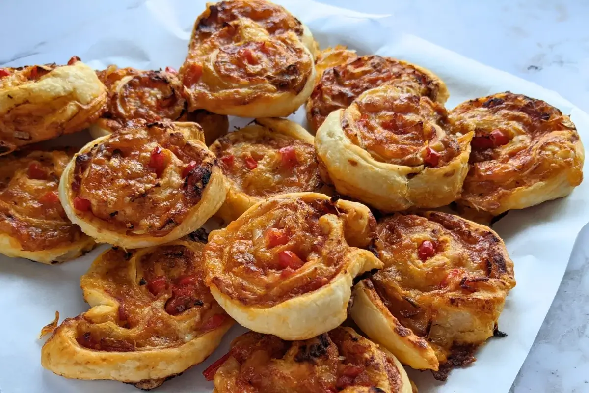Golden brown pizza pinwheels filled with tomato sauce, salami, and melted cheese.