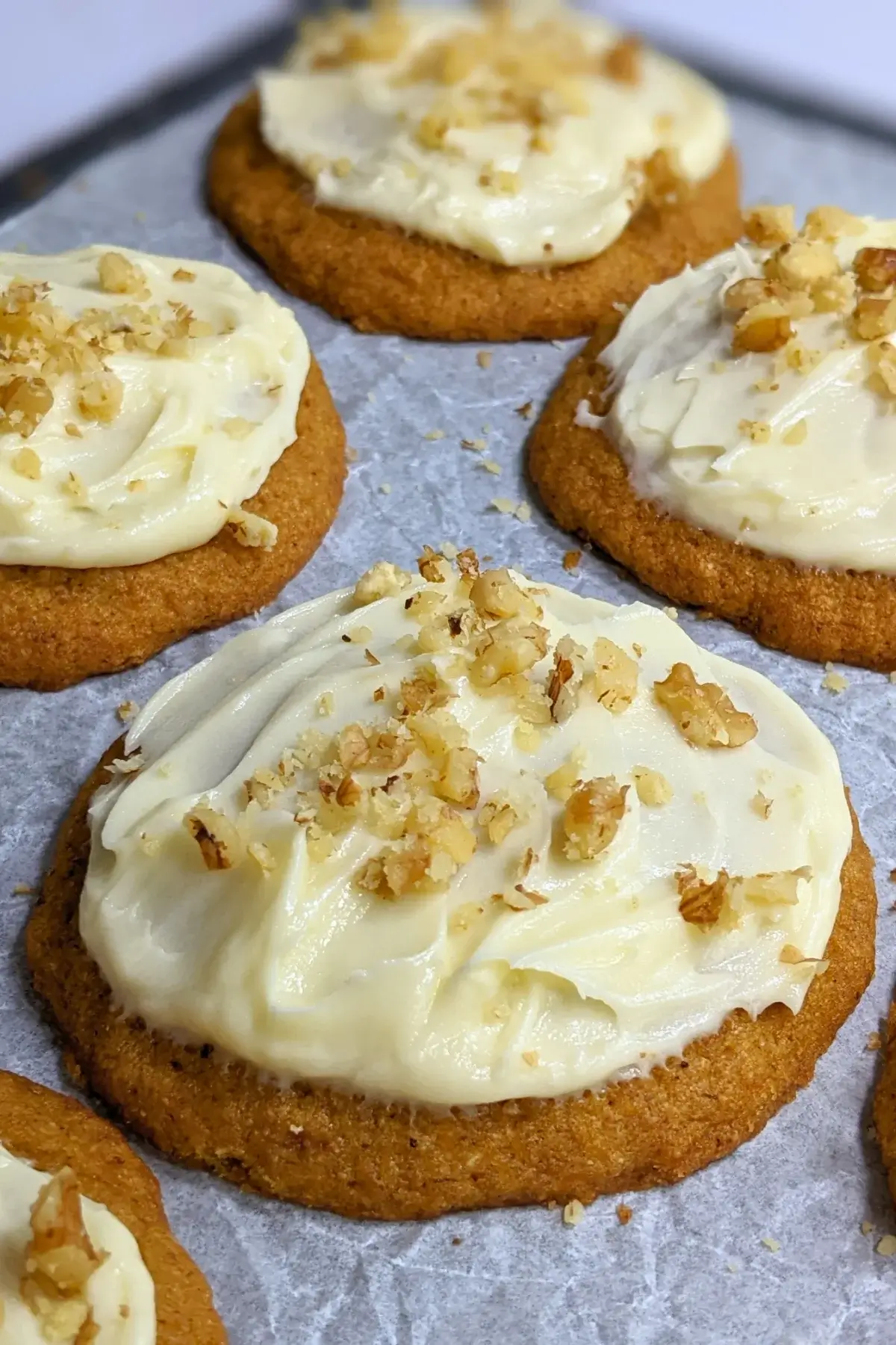 Pumpkin cookies with cream cheese icing made partly with healthier wholemeal flour and coconut sugar, frosted with a cream cheese icing and topped with crushed walnuts for decoration.
