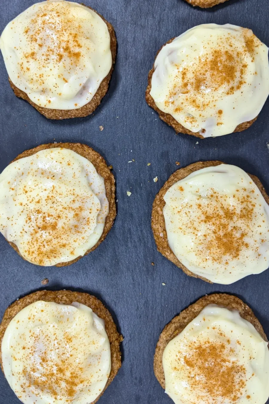 Pumpkin sugar cookies made with healthier wholemeal flour and coconut sugar, frosted with a classic cream cheese icing, and decorated with sprinkles of cinnamon.