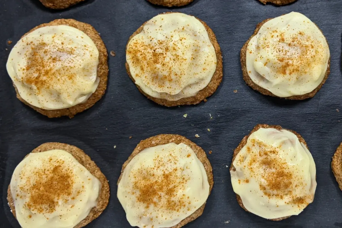 Pumpkin sugar cookies made with healthier wholemeal flour and coconut sugar, frosted with a classic cream cheese icing, and decorated with sprinkles of cinnamon.
