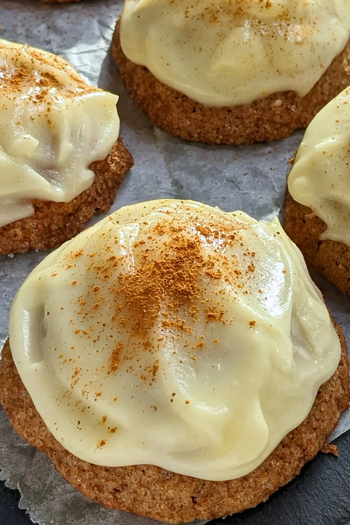 Pumpkin sugar cookies made with healthier wholemeal flour and coconut sugar, frosted with a classic cream cheese icing, and decorated with sprinkles of cinnamon.