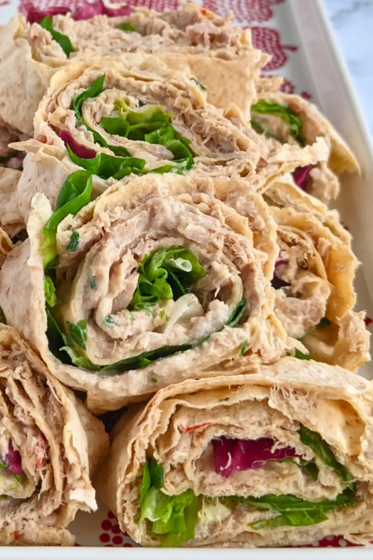 Smoked salmon flatbread appetizers sliced into pinwheels filled with salmon-cream cheese spread and fresh greens.