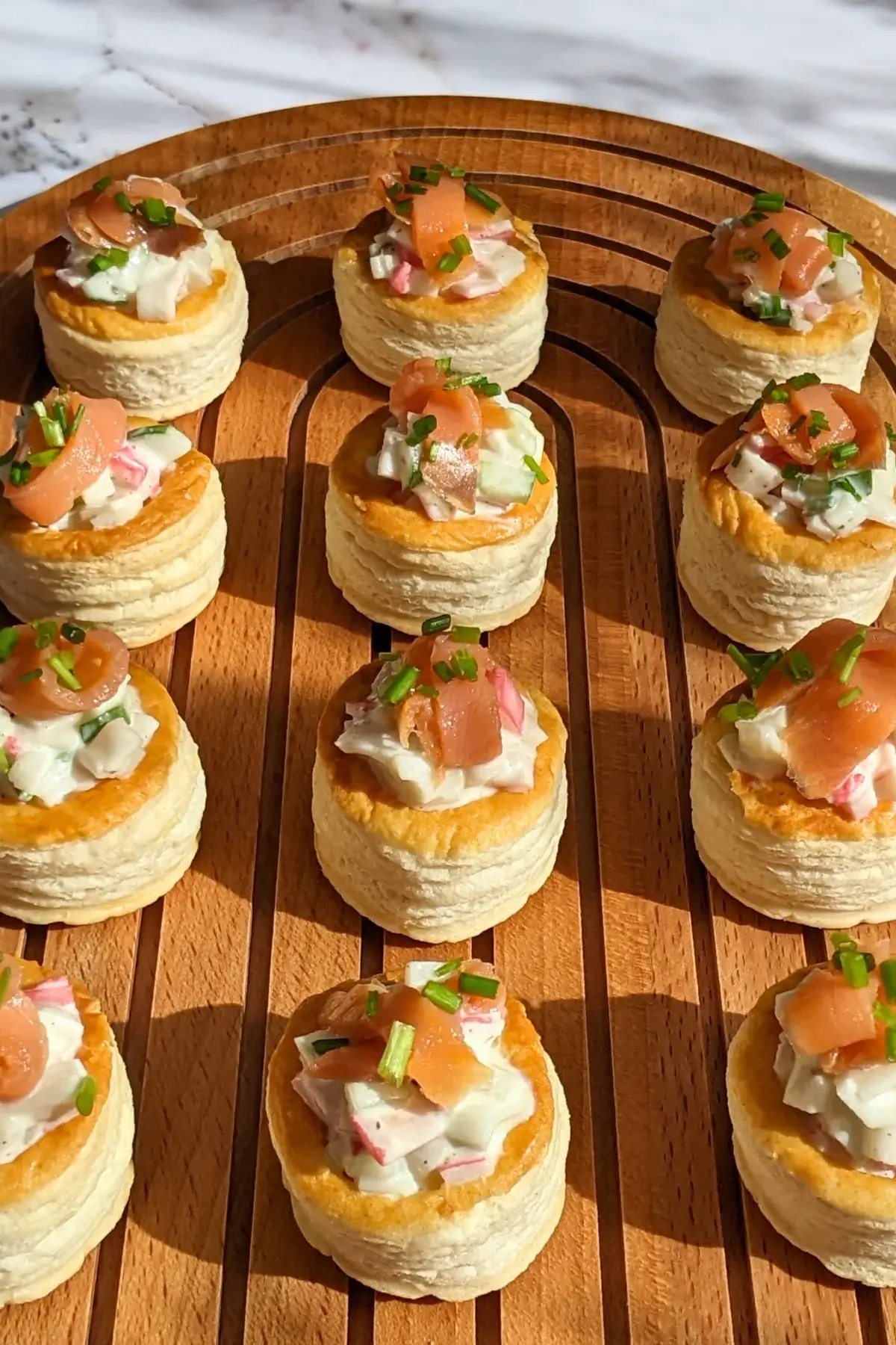 Surimi vol au vent appetizers - puff pastry vol au vent shells filled with a surimi, cucumber, and mayonnaise salad topped with smoked salmon and fresh chives. 